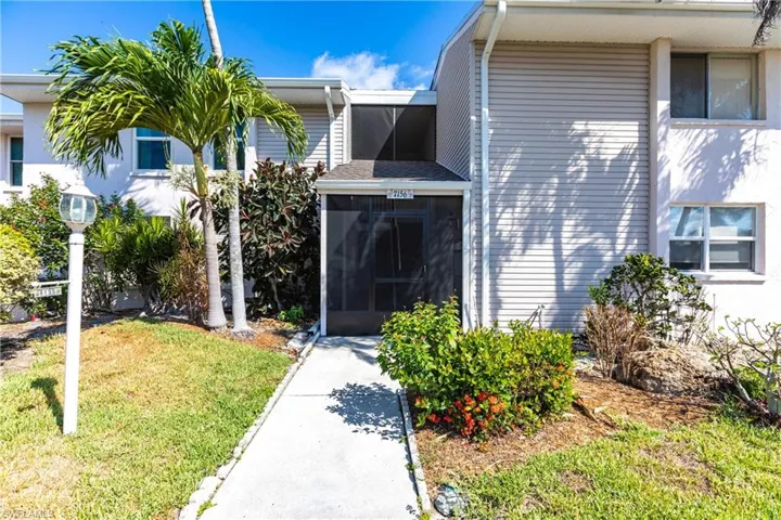 Entrance to property with a lawn, a sunroom, and stucco siding