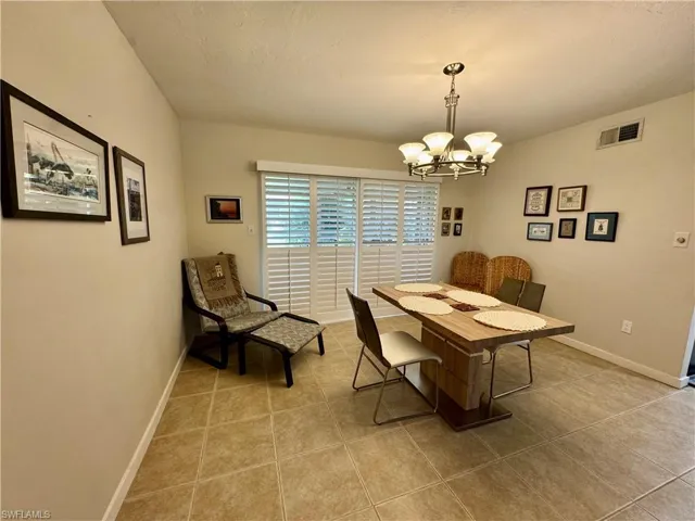 Dining area featuring light tile patterned floors, a chandelier, and a textured ceiling