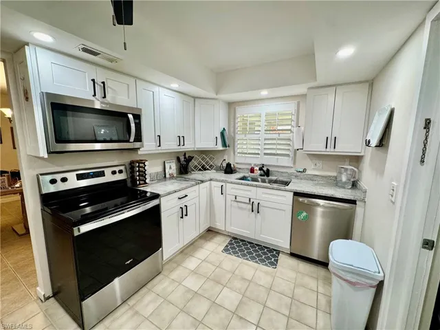 Kitchen with appliances with stainless steel finishes, white cabinets, recessed lighting, and light tile patterned flooring