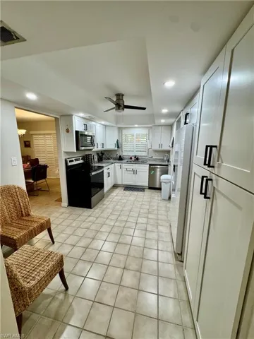 Kitchen featuring white cabinets, stainless steel appliances, recessed lighting, light tile patterned floors, and a ceiling fan