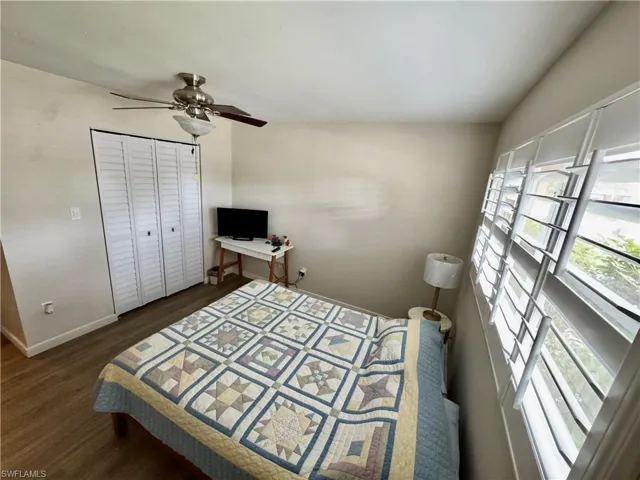 Bedroom with dark wood-style floors, ceiling fan, and a closet
