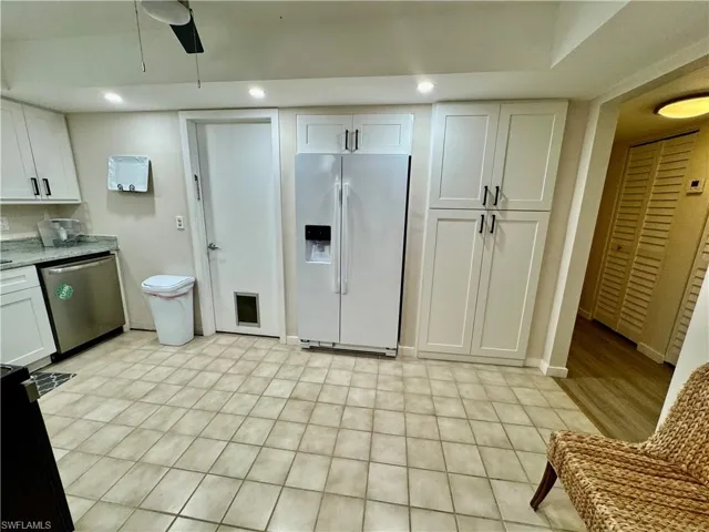 Kitchen with white refrigerator with ice dispenser, white cabinetry, dishwasher, black range oven, and recessed lighting