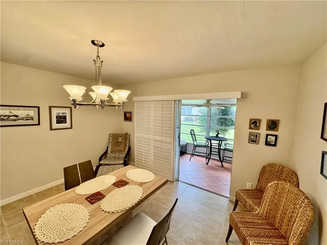 Dining area with light tile patterned flooring, a chandelier, and a textured ceiling