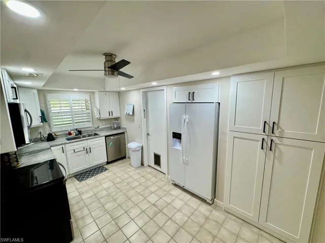 Kitchen with appliances with stainless steel finishes, white cabinetry, recessed lighting, ceiling fan, and light stone counters