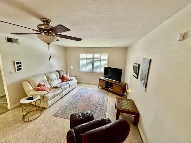 Living area featuring light tile patterned floors, a textured ceiling, and a ceiling fan