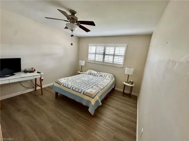 Bedroom with wood finished floors, ceiling fan, and a desk