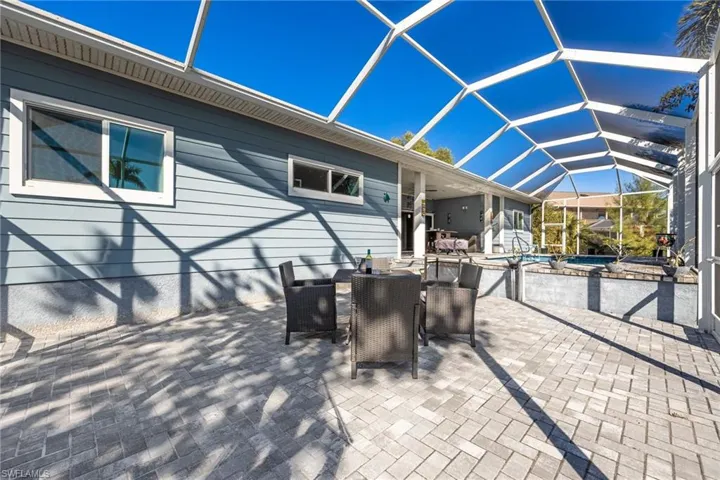 View of patio / terrace featuring outdoor dining space, a sunroom, an outdoor pool, and glass enclosure