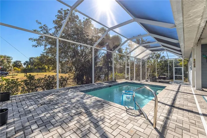 Outdoor pool featuring a sunroom, a lanai, and a patio