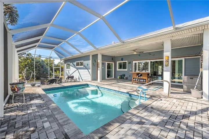 Swimming pool with a sunroom, a patio area, and glass enclosure