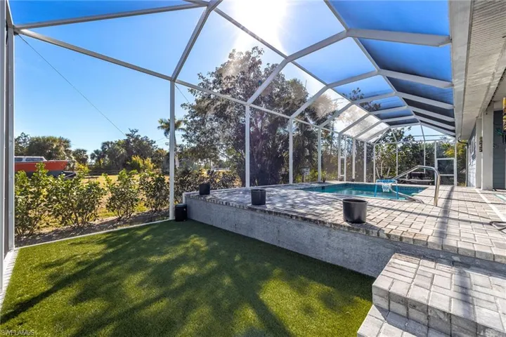 Outdoor pool with a sunroom, glass enclosure, a patio, and a yard