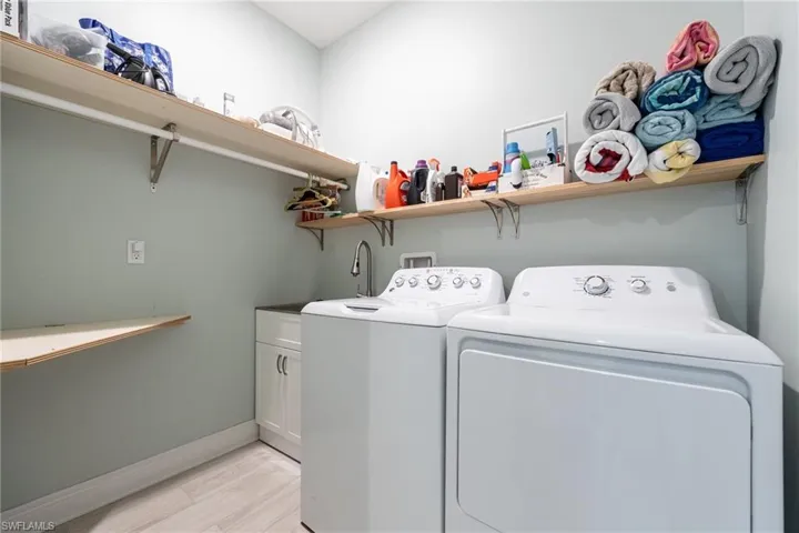 Washroom featuring washing machine and clothes dryer, cabinet space, and light wood finished floors