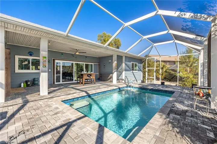 Outdoor pool featuring a patio area, a sunroom, and glass enclosure