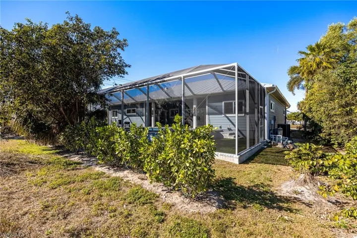 Rear view of house with a sunroom, a lanai, and a lawn
