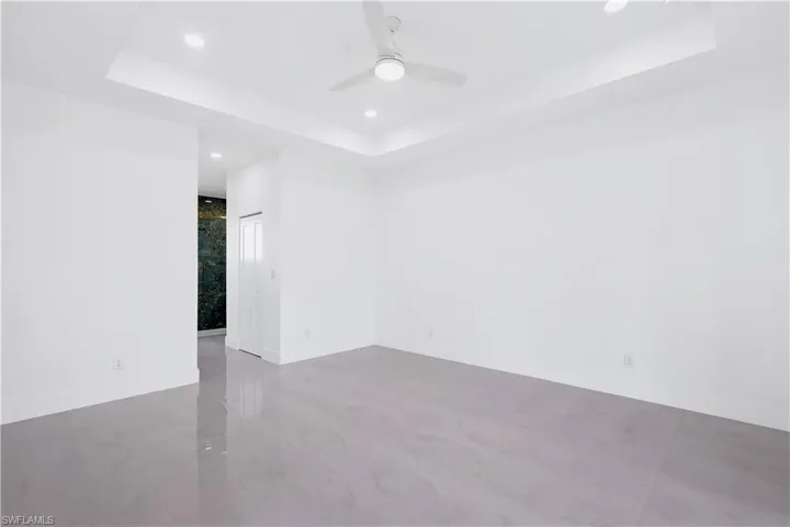 Tiled spare room featuring ceiling fan and a tray ceiling