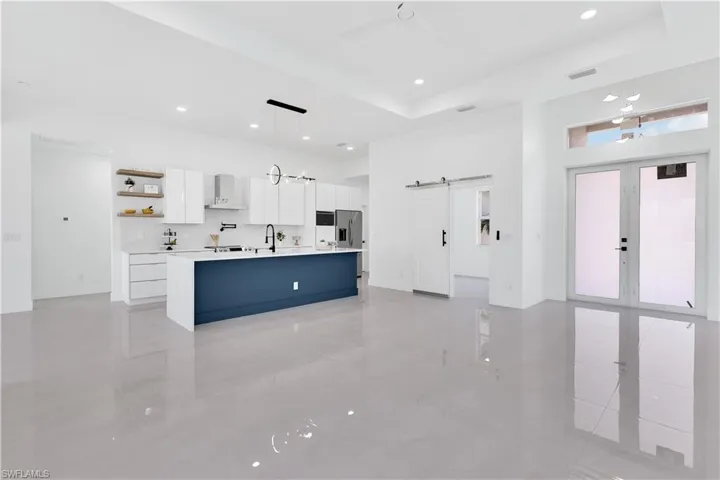 Kitchen with light tile patterned floors, pendant lighting, a center island with sink, and white cabinets