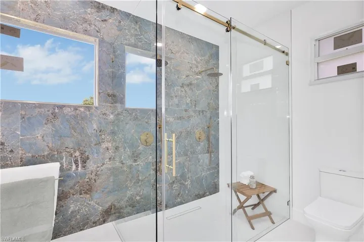 Bathroom with tile patterned floors, tile walls, walk in shower, and toilet