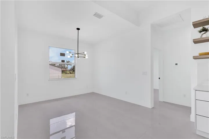 Tiled empty room featuring beam ceiling and an inviting chandelier