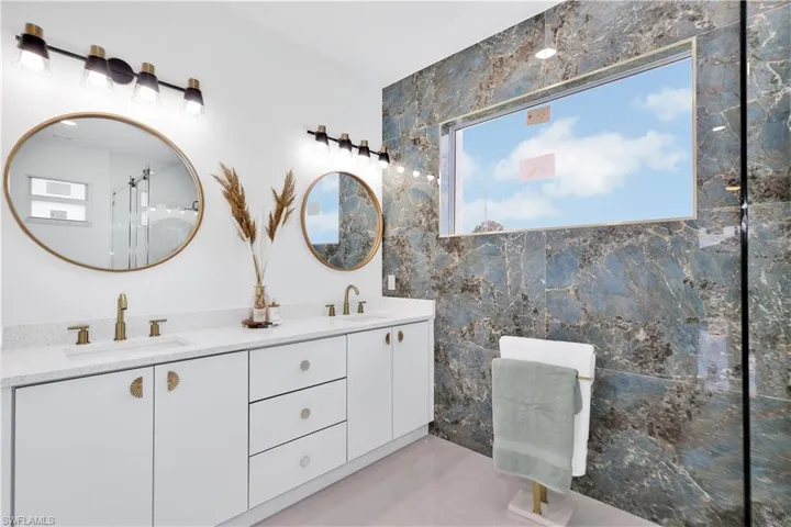 Bathroom featuring a wealth of natural light, tile walls, and dual vanity
