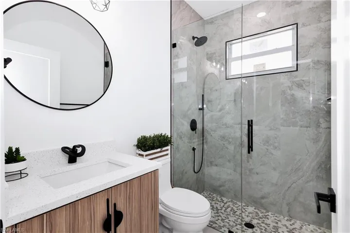 Bathroom with toilet, walk in shower, and vanity