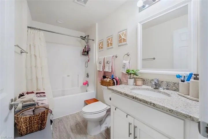 Bathroom with vanity, shower / bathtub combination with curtain, and light wood-type flooring