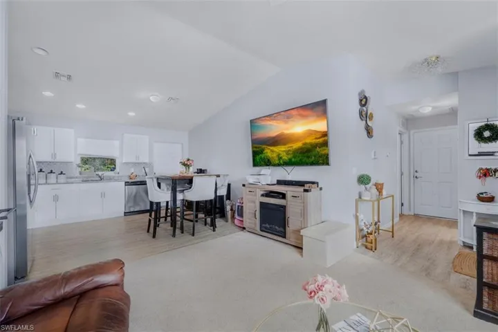 Living area featuring lofted ceiling, light carpet, and light wood-type flooring