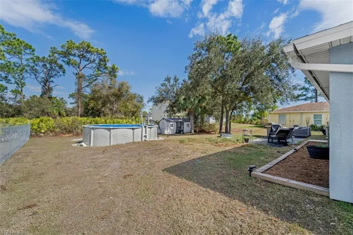 View of yard featuring an outdoor pool, a storage shed, and a patio