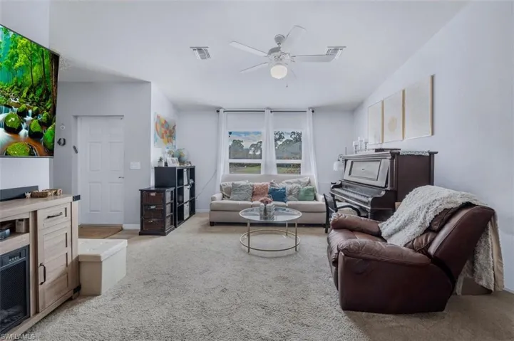 Living area with light colored carpet and a ceiling fan