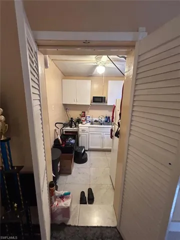 Kitchen with white cabinetry, ceiling fan, freestanding refrigerator, and light tile patterned floors