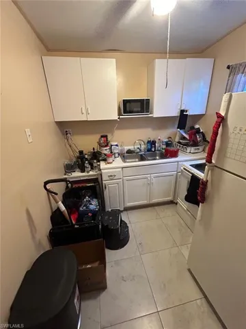 Kitchen with white appliances, white cabinetry, light countertops, and light tile patterned floors