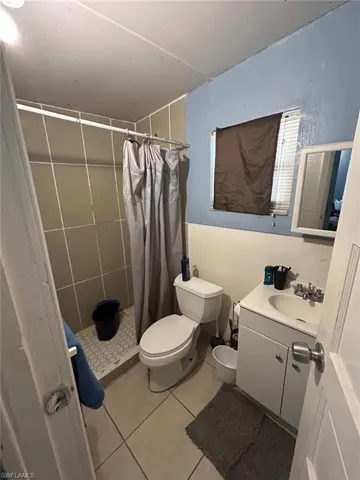Full bathroom with tile walls, tile patterned flooring, vanity, and a stall shower