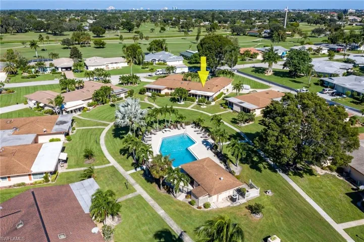 Aerial view showcasing the property with a brown shingle roof, surrounded by green lawns and mature landscaping