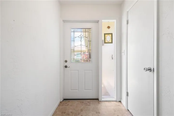 Entryway featuring a white paneled door with decorative glass inserts, a full-length sidelight, and textured white walls