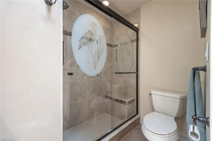 Framed glass shower enclosure featuring an etched design and tiled interior