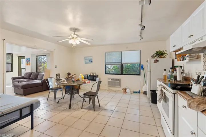 Dining room with a ceiling fan, rail lighting, light tile patterned floors, and a wall mounted AC
