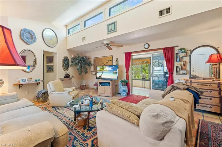 Living room featuring a wealth of natural light, visible vents, a high ceiling, and tile patterned floors