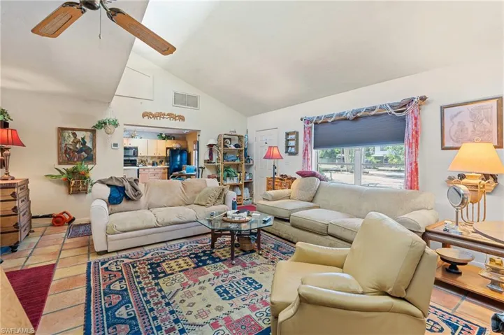 Living room with light tile patterned floors, high vaulted ceiling, ceiling fan, and visible vents