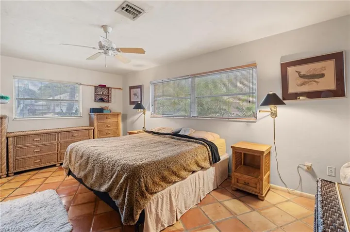 Bedroom with ceiling fan, light tile patterned flooring, visible vents, and baseboards