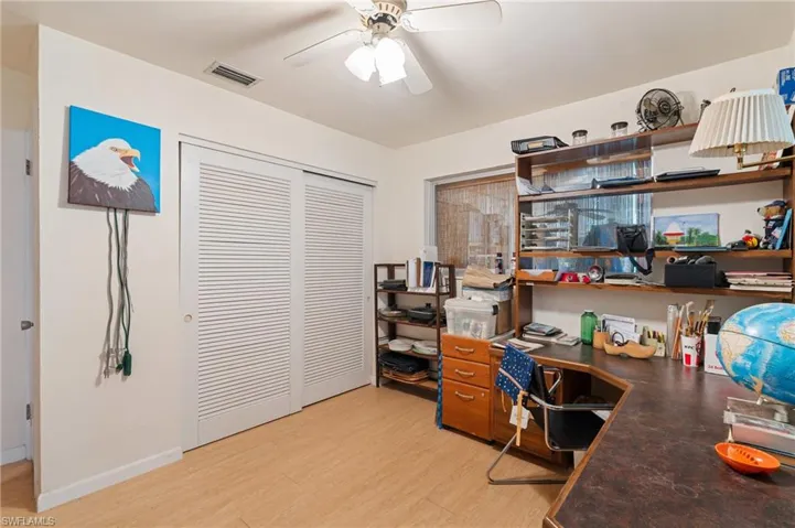 Office space with light wood-style floors, ceiling fan, visible vents, and baseboards