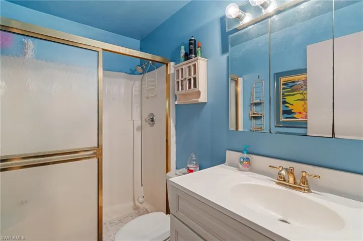 Bathroom featuring a stall shower, vanity, and toilet