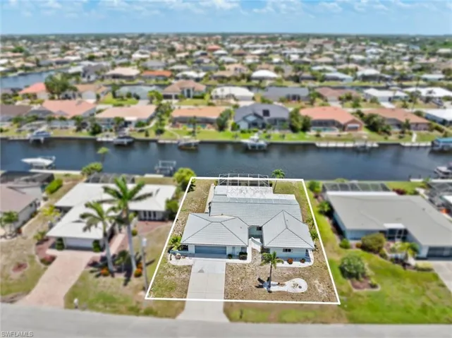 Aerial view of residential area featuring property parcel outlined and a nearby body of water