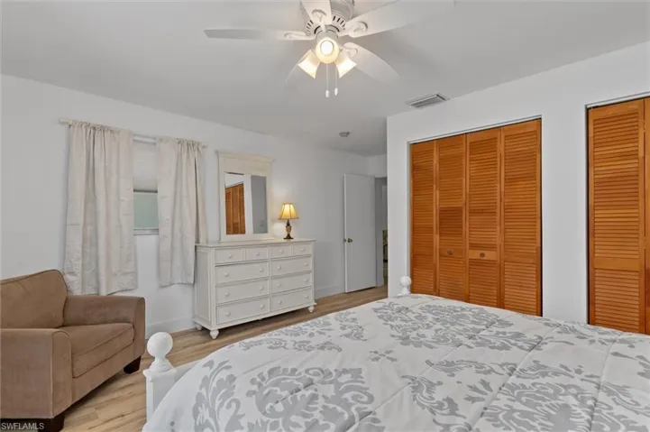 Guest Bedroom featuring wood finished floors, two closets, and ceiling fan