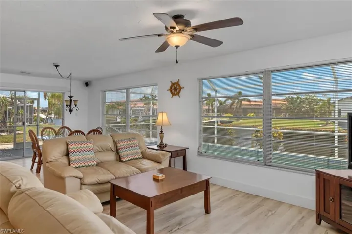 Living area featuring light wood-style flooring, a ceiling fan, and a chandelier