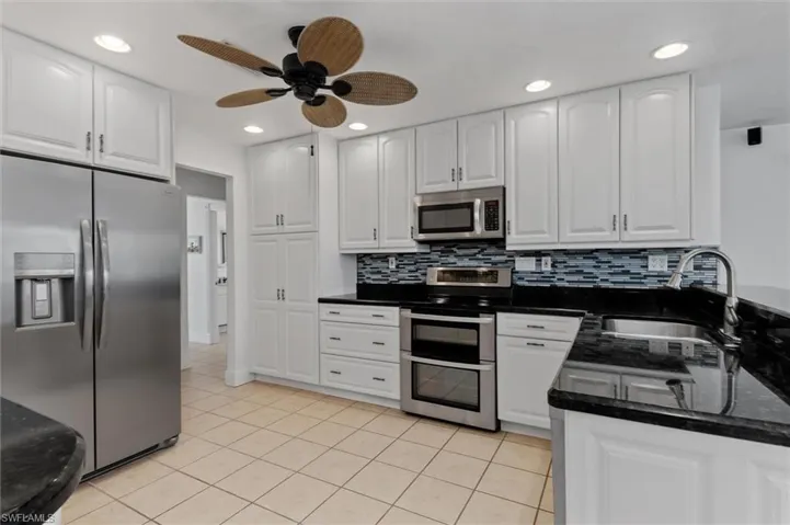 Kitchen with appliances with stainless steel finishes, tasteful backsplash, recessed lighting, white cabinetry, and light tile patterned floors