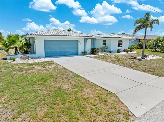 Single story home featuring a garage, stucco siding, a front yard, a tiled roof, and driveway