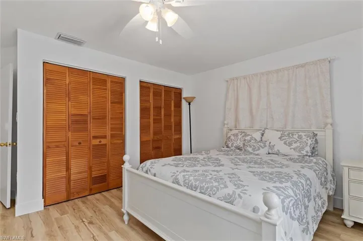 Guest Bedroom featuring two closets, light wood-style flooring, and a ceiling fan