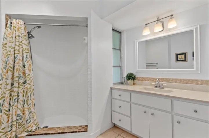 Bathroom featuring vanity, a tile shower, and tile patterned floors