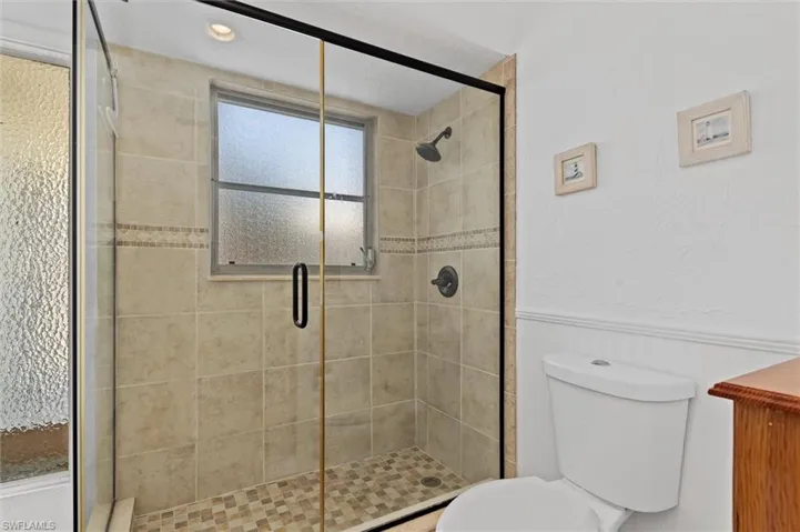 Full bathroom with wainscoting, a shower stall, and a decorative wall