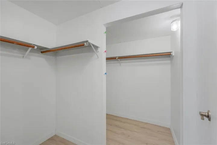 Double walk in closet with light hardwood-style flooring