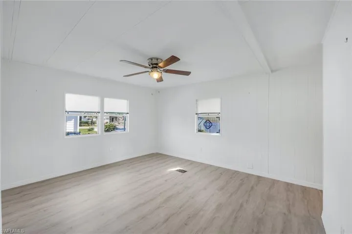 Primary bedroom with ceiling fan and light hardwood-style flooring