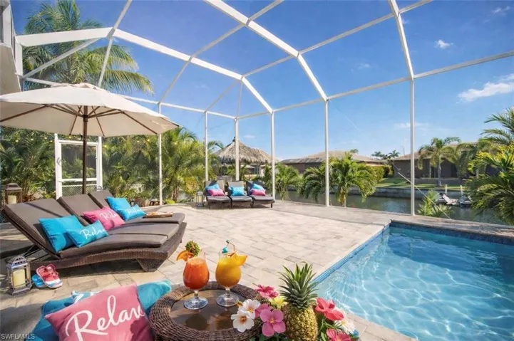 Outdoor pool with a lanai, a sunroom, a water view, and a patio area